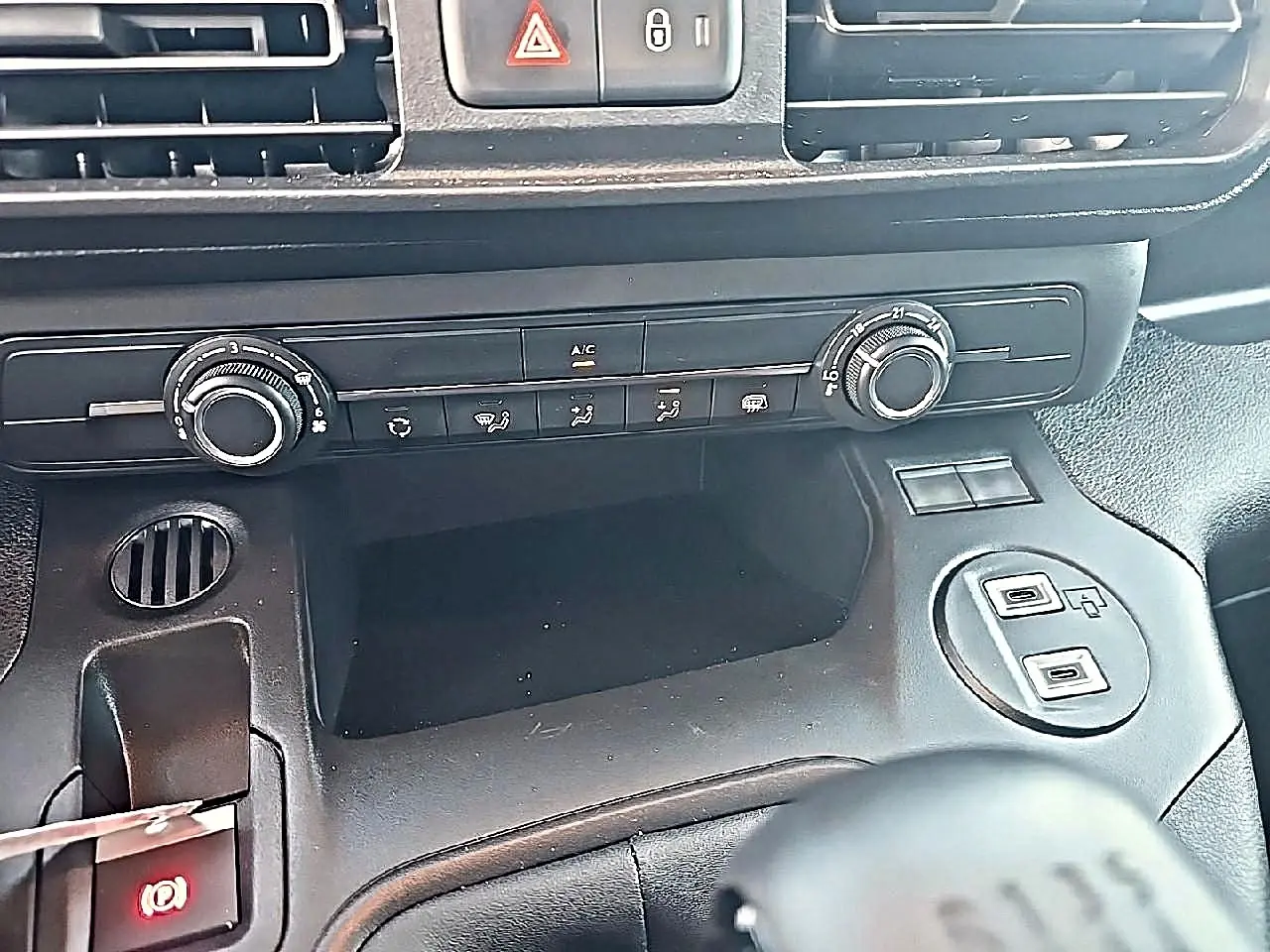 Vue rapprochée de la console centrale noire du Citroën Berlingo Fourgon avec commandes clim et prises USB visibles.