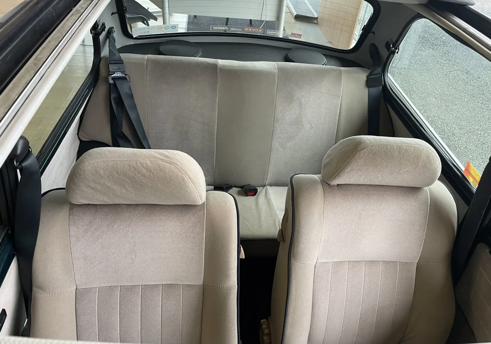 Vue intérieure arrière montrant les sièges beige clair d'une MINI 1.3 i British Open 1995, avec ceinture de sécurité noire.
