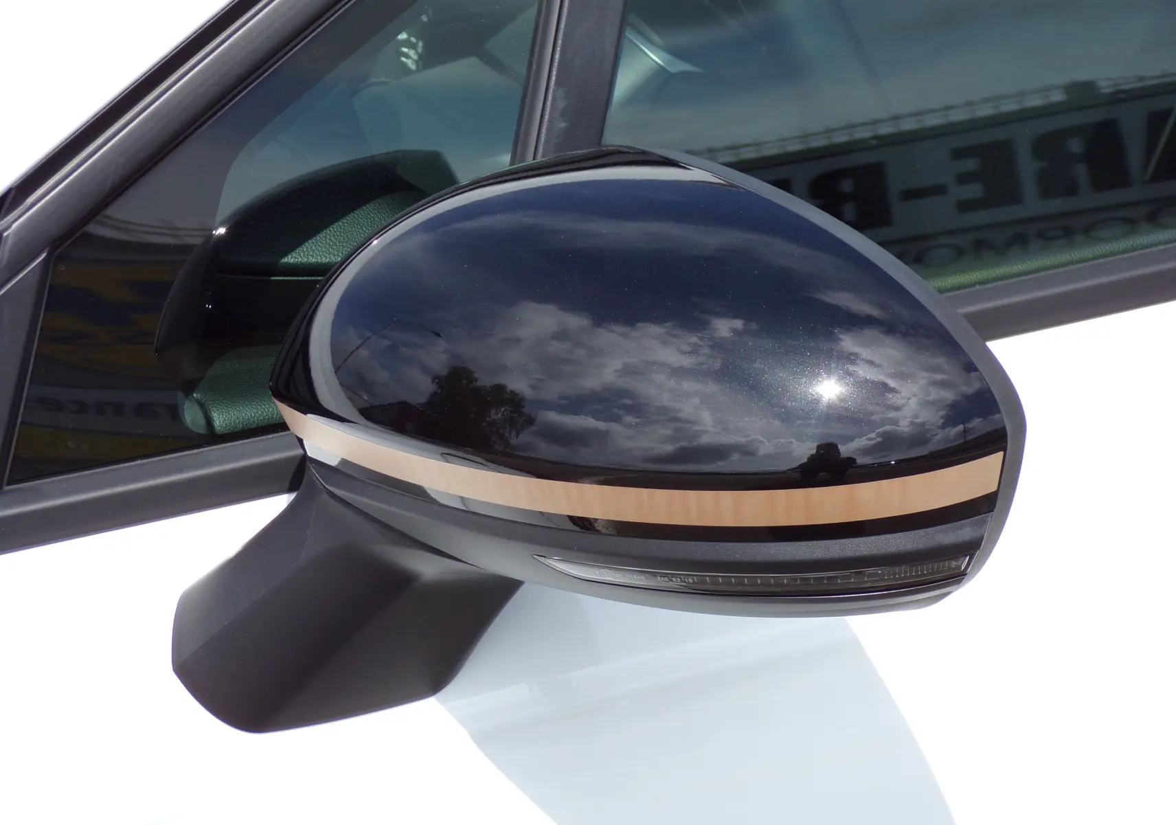 Rétroviseur côté gauche noir brillant avec bande beige sur Renault Clio V blanche essence 2022, vue rapprochée.