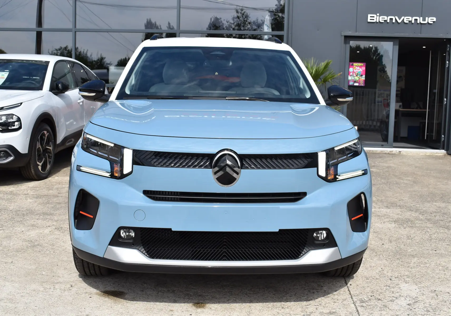 Vue frontale d'une Citroën C3 2025 bleu clair avec toit noir, feux LED et calandre noire distinctive.