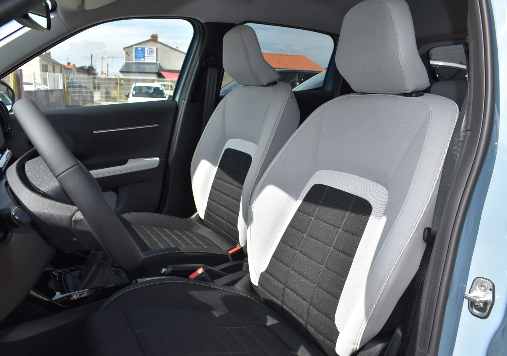 Vue intérieure côté conducteur de la Citroën C3 2025 bleu toit noir, sièges avant bicolores gris et noir avec appuie-têtes intégrés.