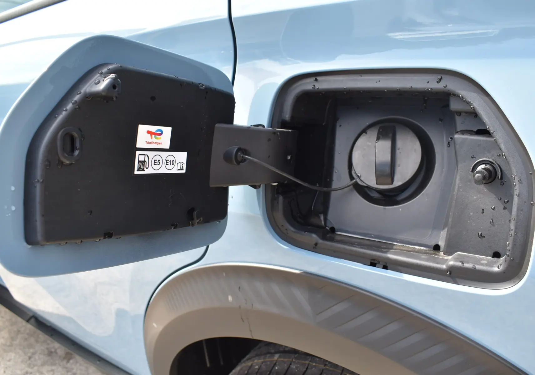 Gros plan sur la trappe à carburant ouverte côté gauche d'une Citroën C3 2025 bleu toit noir.