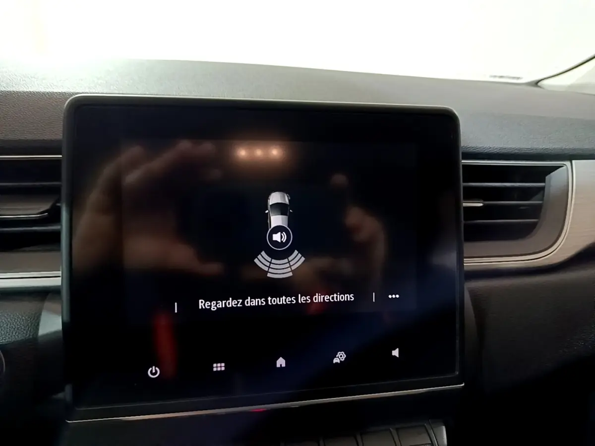 Écran tactile central du tableau de bord du Renault Captur gris clair, affichant une alerte de détection d'obstacles.