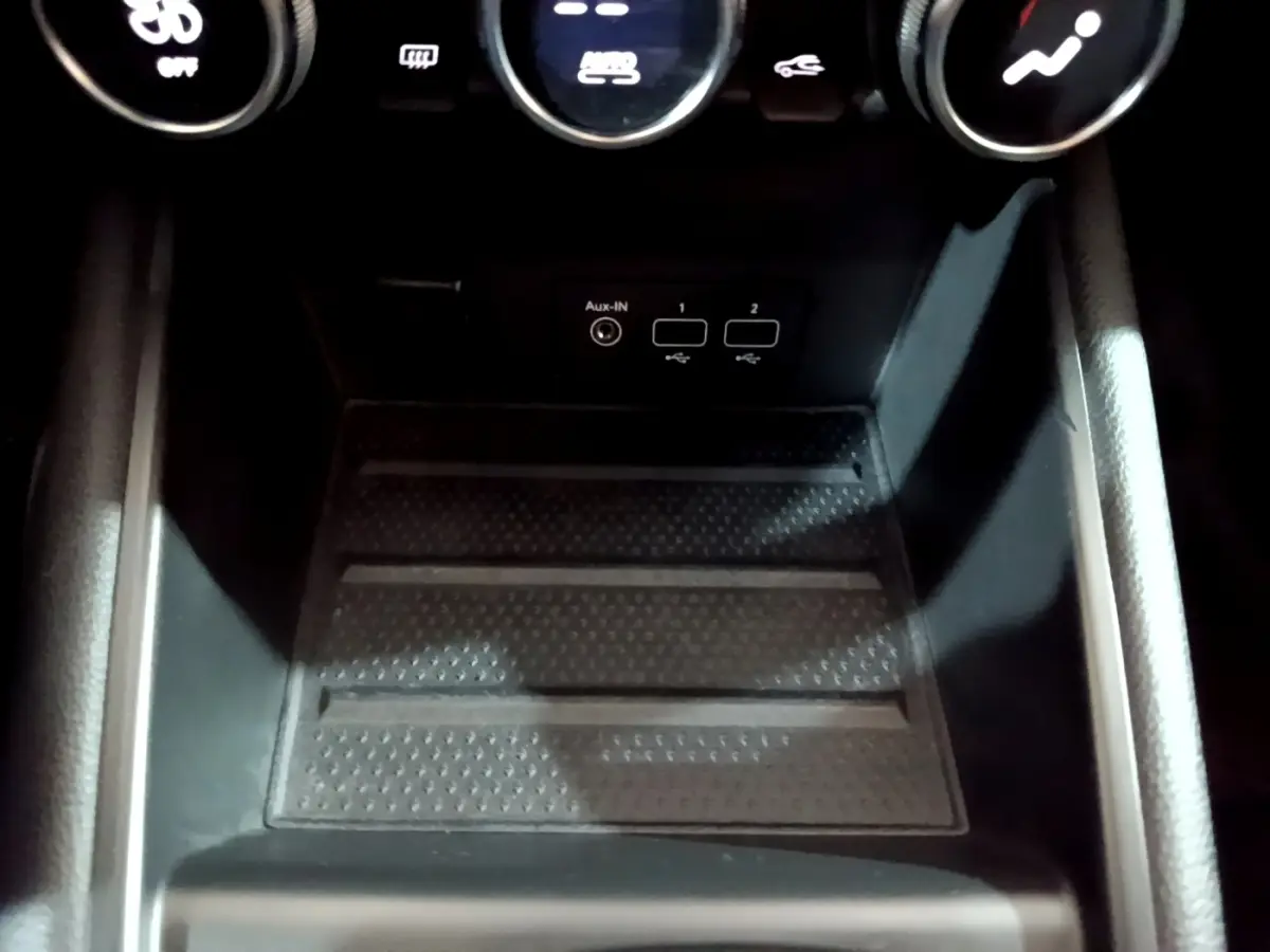 Gros plan sur la console centrale noire du Renault Captur Intens E-Tech 2021, montrant ports USB et bouton de climatisation.