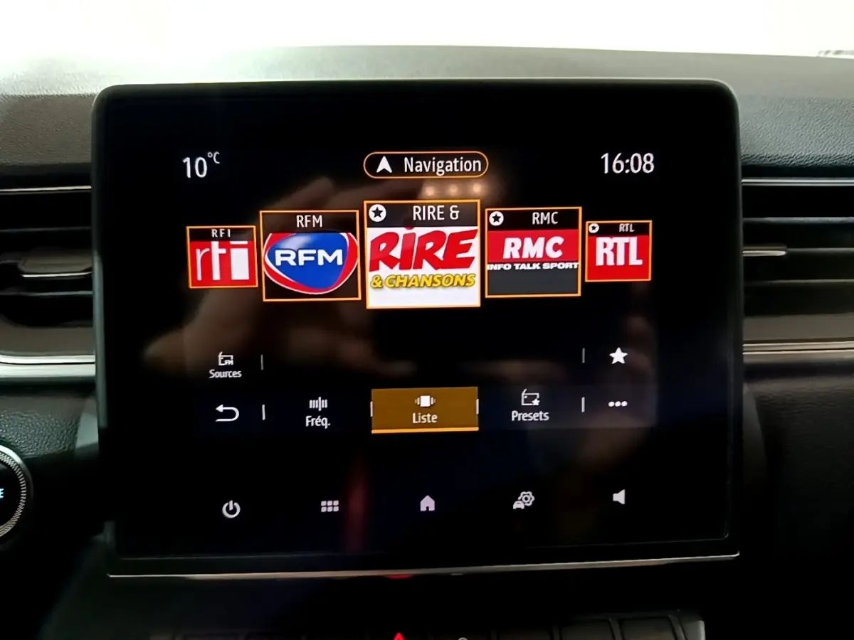 Écran tactile central du tableau de bord du Renault Captur gris clair, affichant les stations radio en mode navigation.
