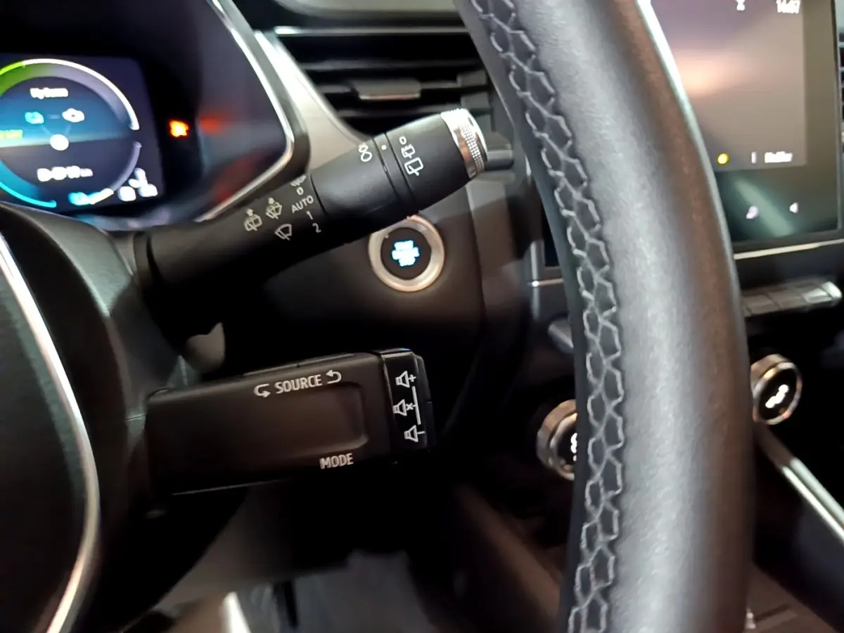 Gros plan intérieur sur le volant cuir et commandes multifonctions du Renault Captur Intens E-Tech hybride gris clair.