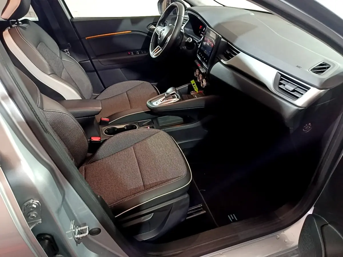 Vue intérieure côté conducteur du Renault Captur gris clair 2021 avec tableau de bord moderne et sièges tissu gris.