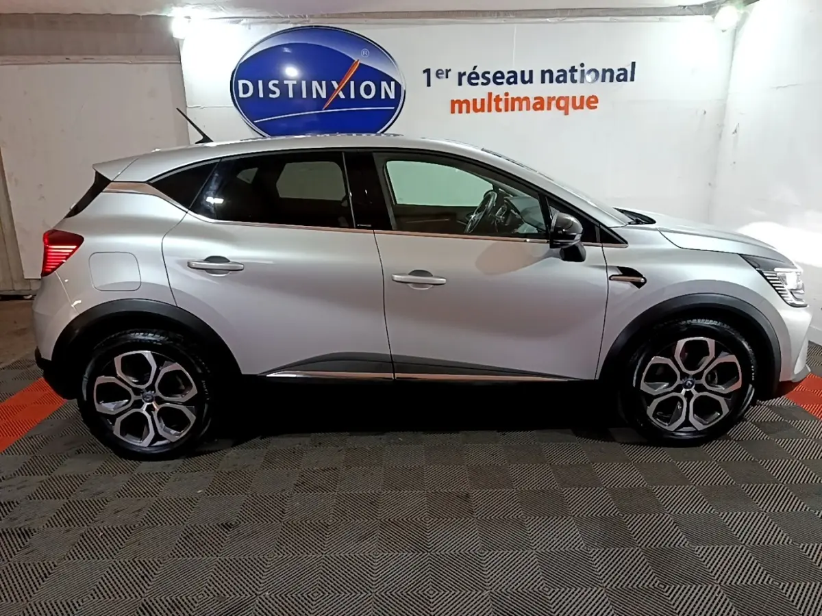 Vue de profil côté gauche d'un Renault Captur gris clair Intens E-Tech hybride rechargeable 2021 dans un showroom.