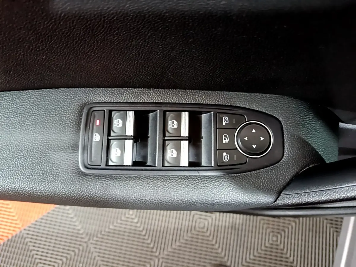 Vue rapprochée des commandes de lève-vitres et rétroviseurs sur la porte côté gauche d’un Renault Captur gris clair.