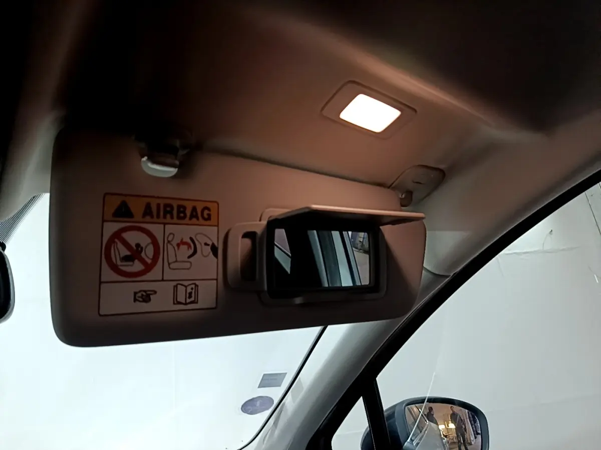 Détail du pare-soleil côté conducteur avec miroir éclairé et avertissement airbag dans un Renault Captur gris clair.