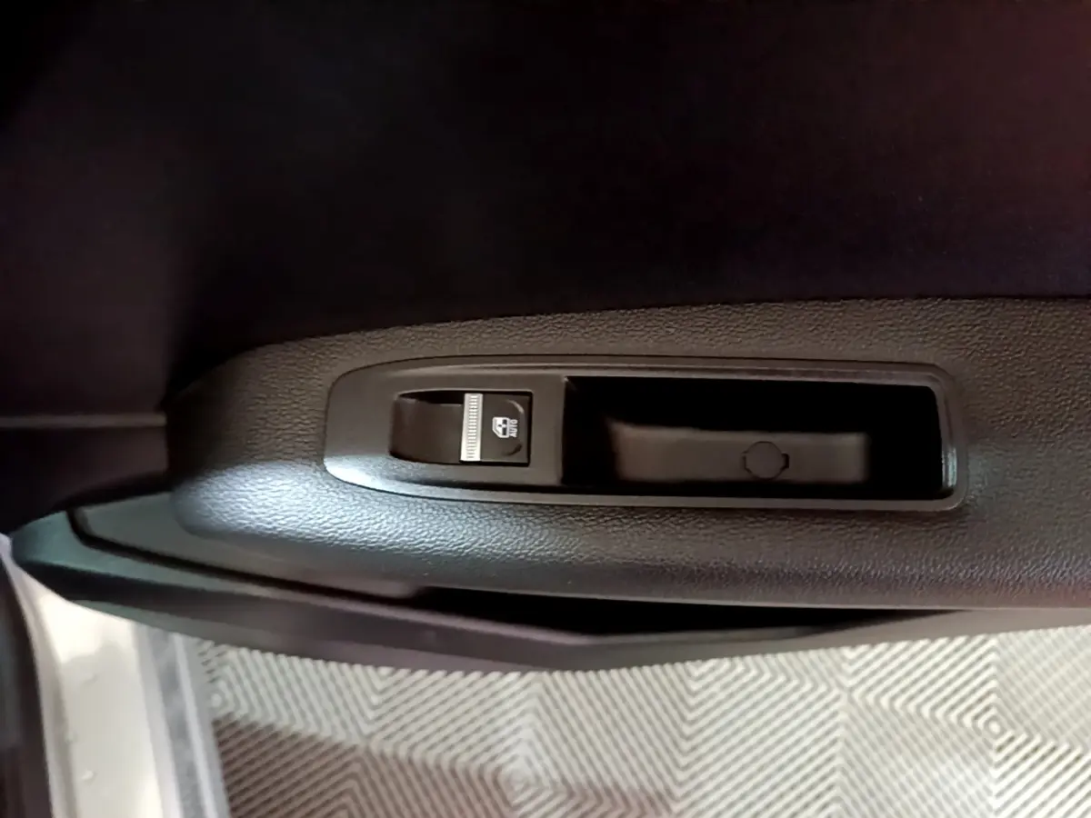 Détail du bouton de verrouillage des vitres sur la porte intérieure côté gauche d’un Renault Captur gris clair.