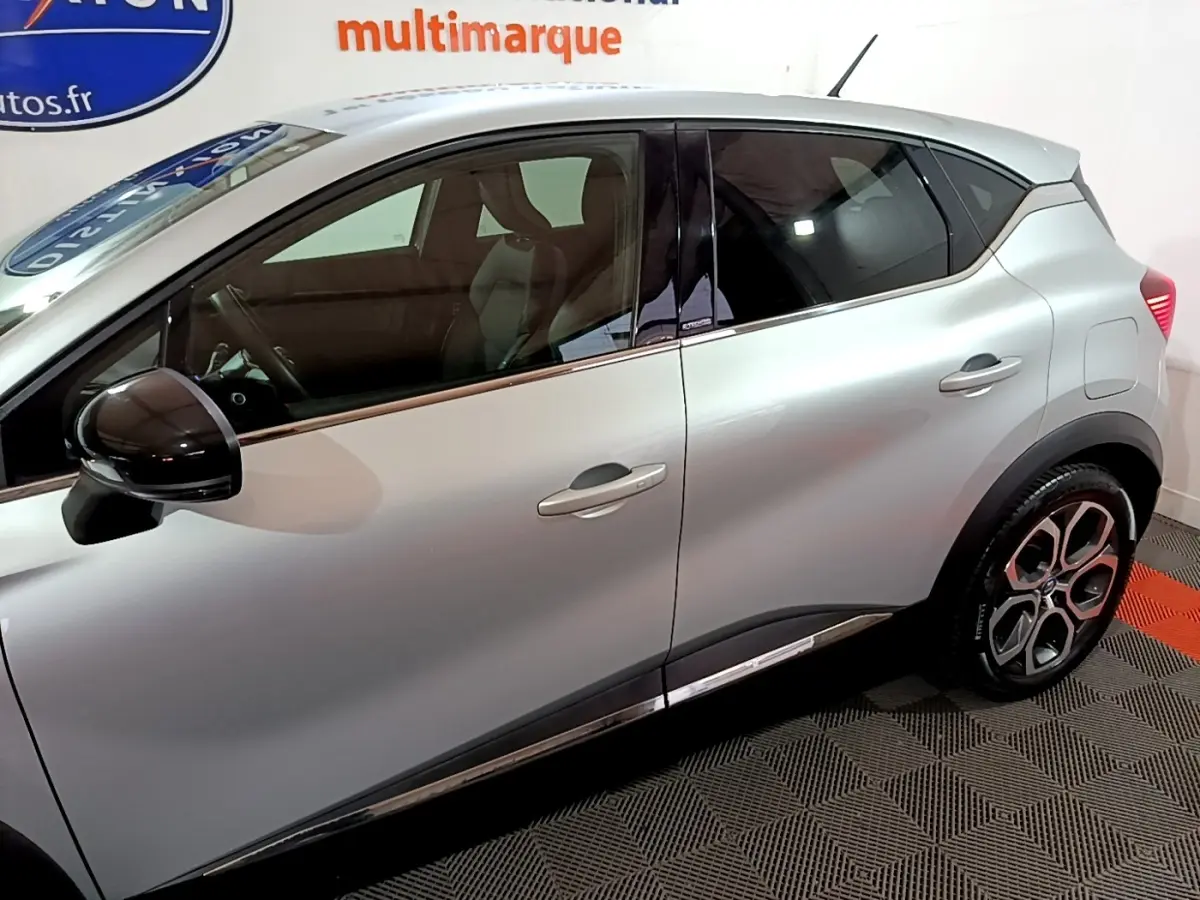 Profil droit du Renault Captur Intens E-Tech hybride rechargeable gris clair, avec rétroviseur noir et jantes distinctives.