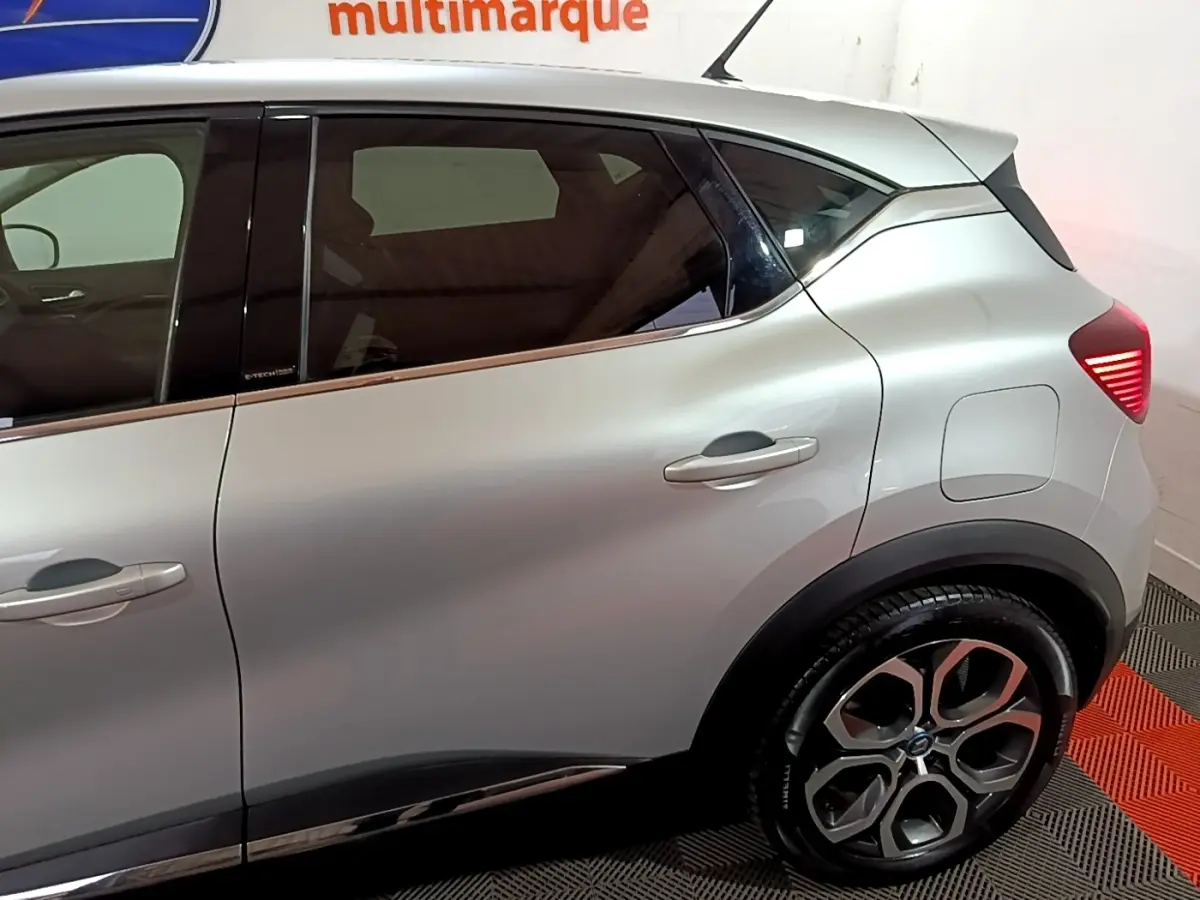 Vue côté droit arrière du Renault Captur gris clair hybride rechargeable avec jantes alliage et feux arrière LED allumés.