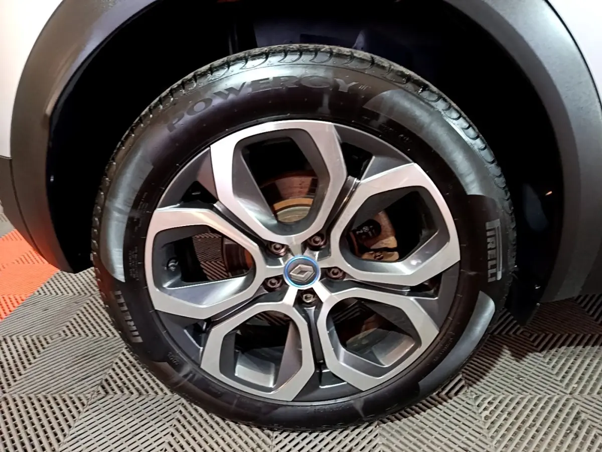 Gros plan sur la roue avant droite du Renault Captur gris clair, avec jante alliage au design moderne et logo Renault central.