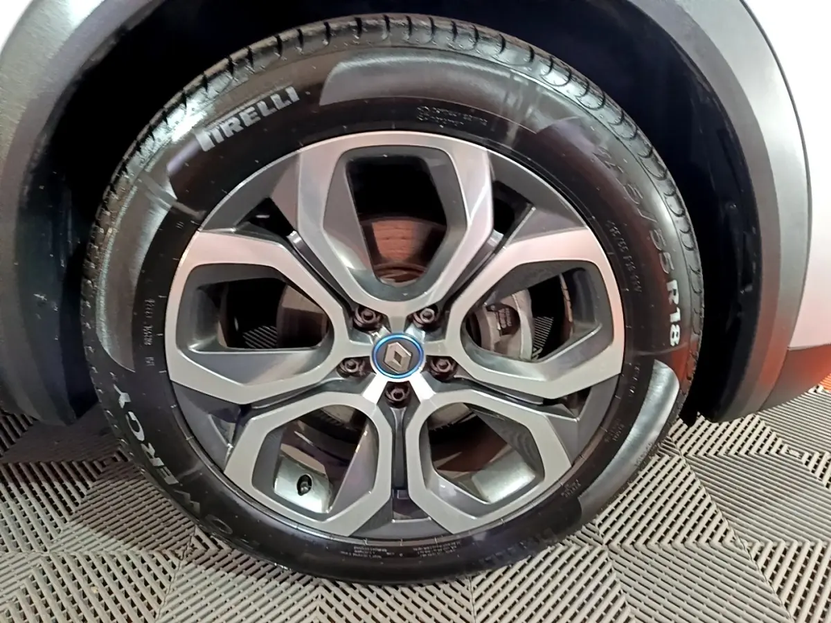 Gros plan sur la roue avant droite du Renault Captur gris clair, avec jante alliage et logo Renault central.