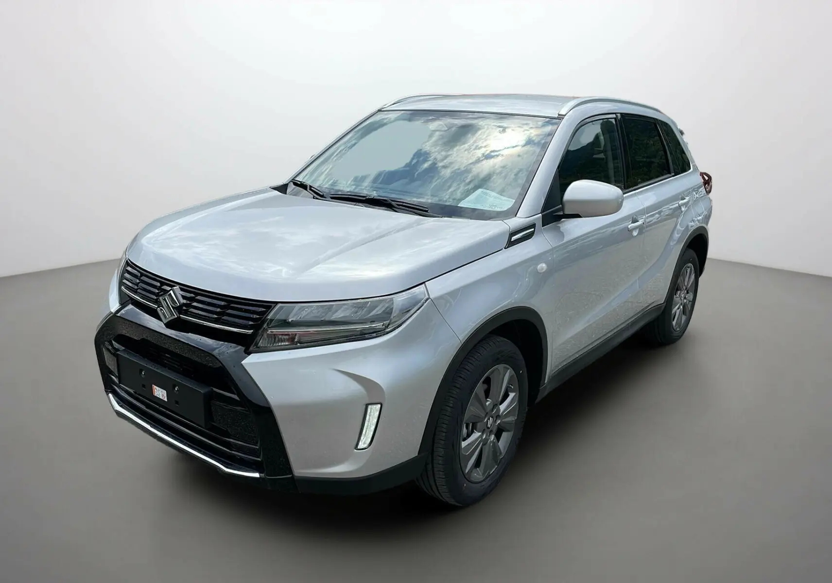 Suzuki Vitara 2025 Silky Silver vue 3/4 avant droit avec calandre noire et feux LED distinctifs.