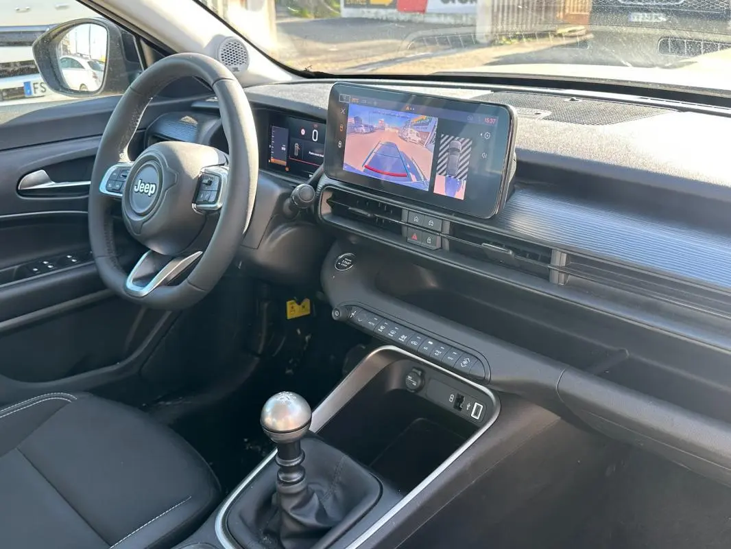 Intérieur du Jeep Avenger gris 2025 vu côté conducteur, avec tableau de bord numérique et caméra de recul affichée.