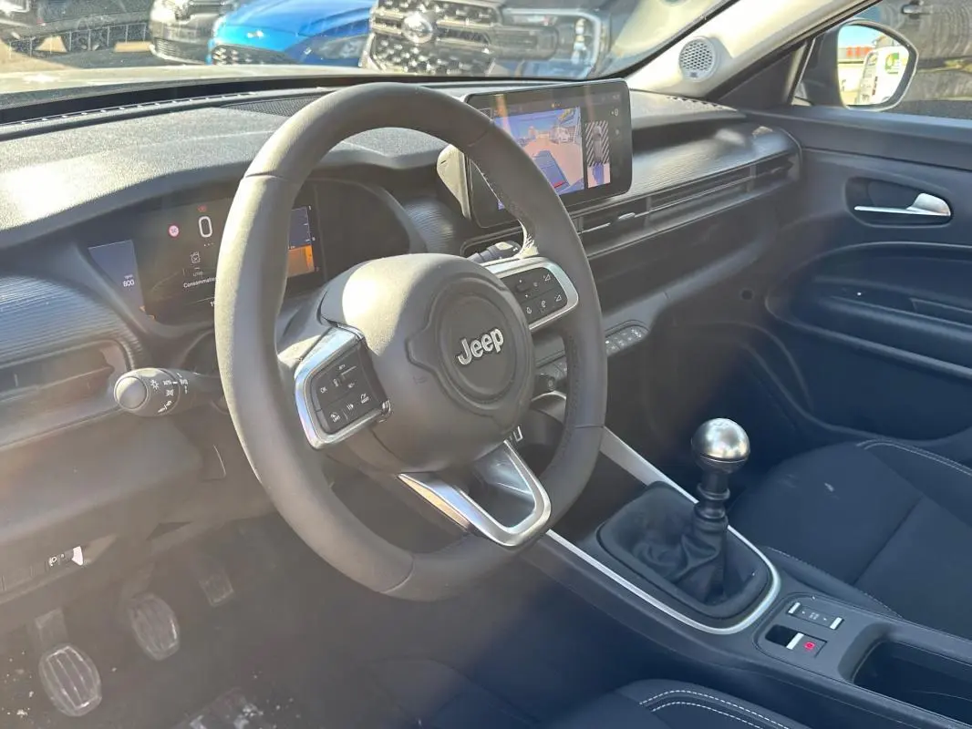 Intérieur du Jeep Avenger gris, vue côté conducteur, volant multifonction et levier de vitesse manuel visible.