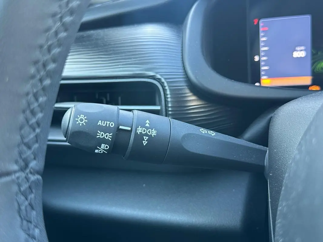 Gros plan sur la commande d'éclairage à gauche du volant dans l'habitacle du Jeep Avenger gris 2025.