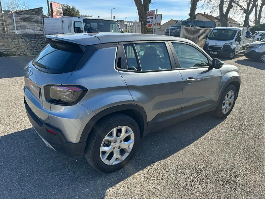 Vue 3/4 arrière droite d'un Jeep Avenger gris 2025 avec jantes alliage 17 pouces et feux arrière teintés.