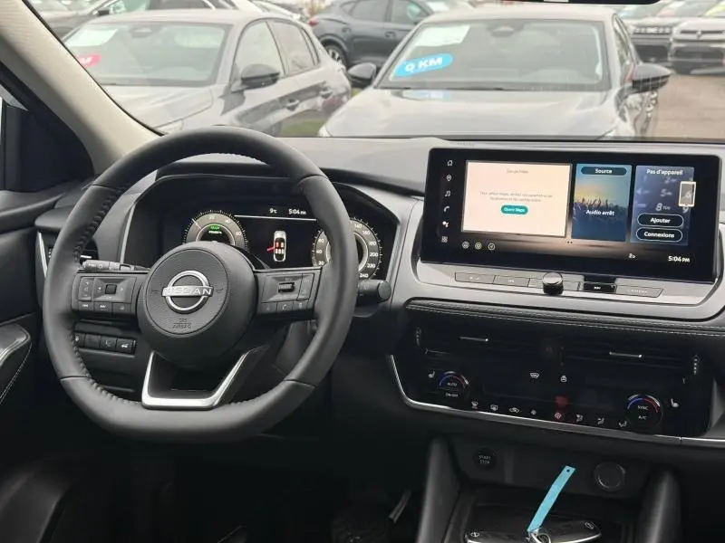 Vue intérieure du tableau de bord et volant du Nissan Qashqai Hybrid e-POWER 2025, avec écran tactile et commandes au volant.