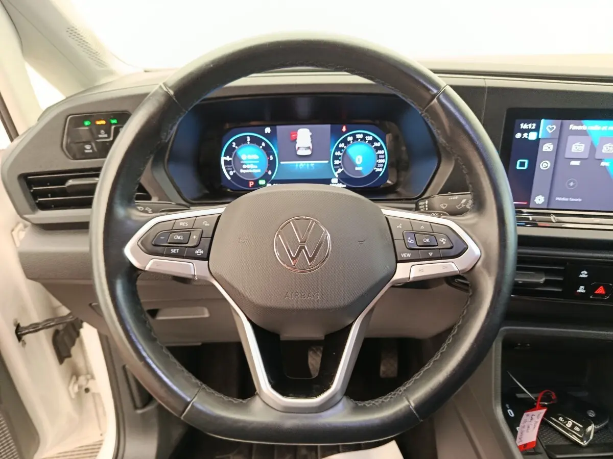 Vue centrée sur le volant cuir noir du Volkswagen Caddy 2022 avec tableau de bord digital et écran tactile.
