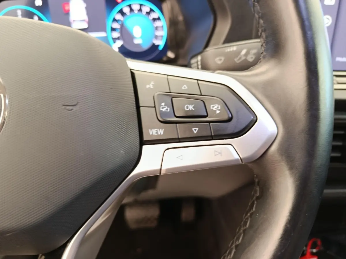 Gros plan sur le volant cuir multifonctions du Volkswagen Caddy 2022 avec commandes intégrées et tableau de bord numérique.