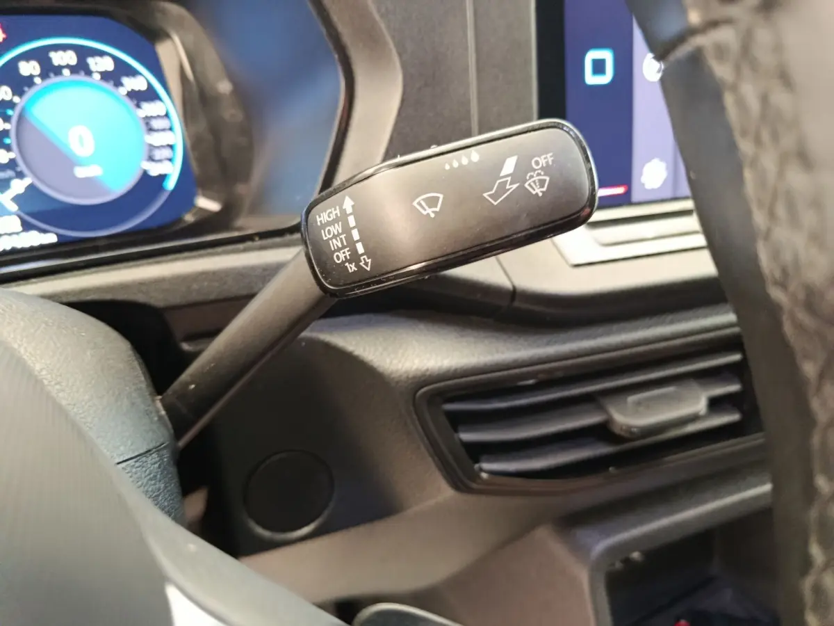 Gros plan sur la commande d’essuie-glace à gauche du volant dans l’habitacle du Volkswagen Caddy blanc 2022.
