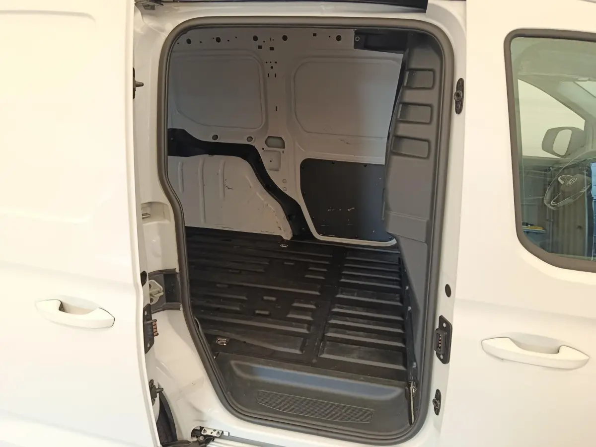 Vue latérale droite du Volkswagen Caddy blanc 2022 avec porte coulissante ouverte montrant l’espace de chargement vide.