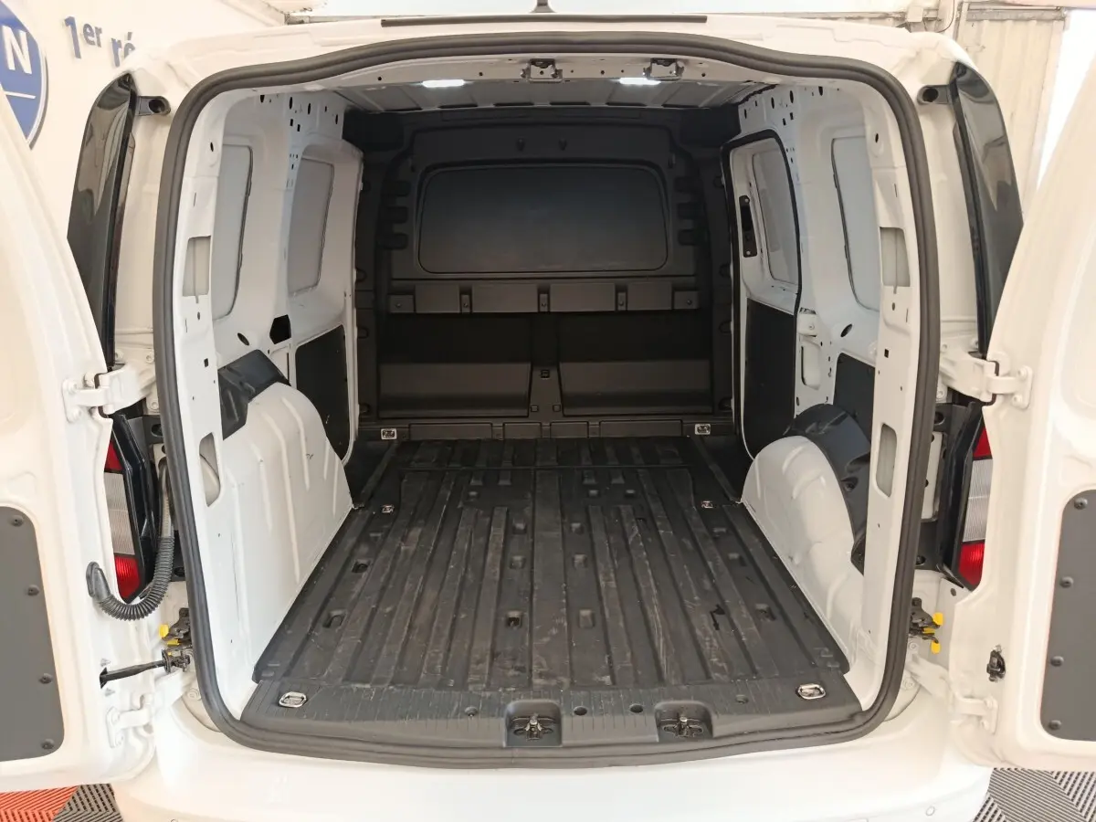 Vue arrière du Volkswagen Caddy blanc 2022 montrant l'espace de chargement vide et les portes battantes ouvertes.