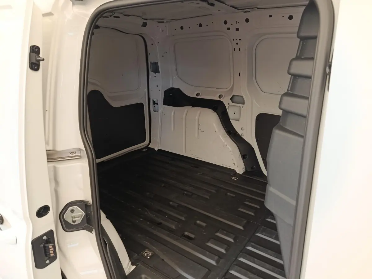 Vue intérieure arrière du coffre blanc du Volkswagen Caddy 2.0 TDI 122ch avec plancher noir et parois métalliques.