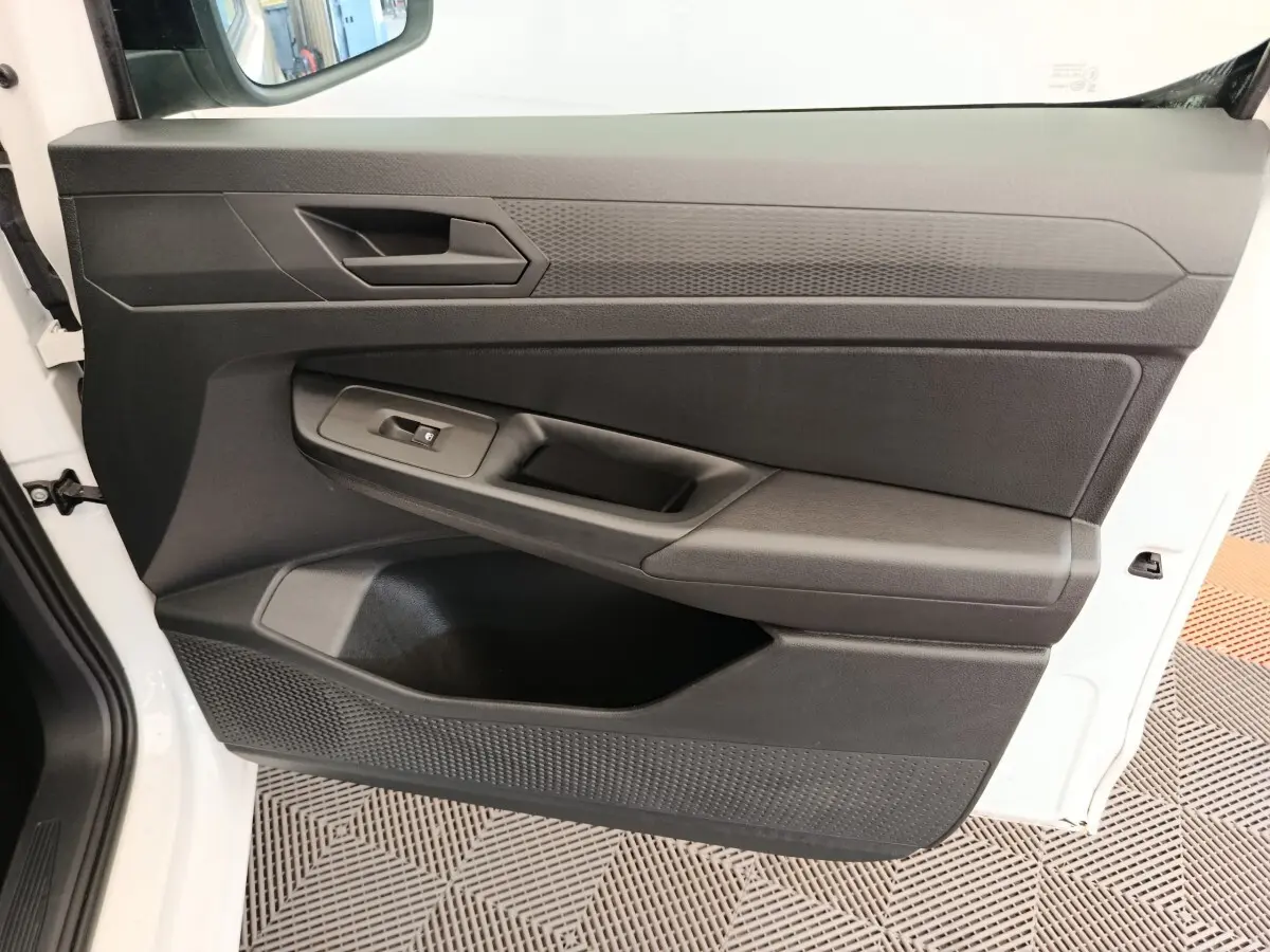 Détail de la porte avant gauche noire du Volkswagen Caddy blanc 2022, avec poignée et commande de vitre électrique.