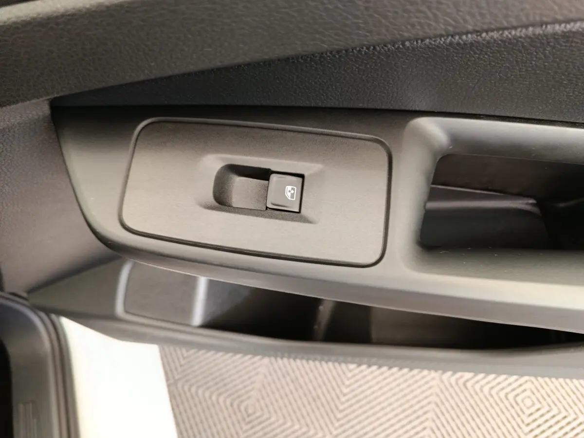 Gros plan sur le bouton de commande de la vitre électrique côté conducteur dans une Volkswagen Caddy blanche.
