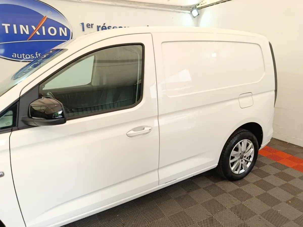 Vue latérale droite d'un utilitaire Volkswagen Caddy blanc avec jantes alliage et rétroviseurs noirs.