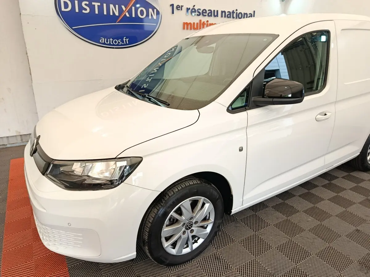 Vue 3/4 avant droit d'un Volkswagen Caddy blanc 2022 avec jantes alliage et rétroviseurs noirs.