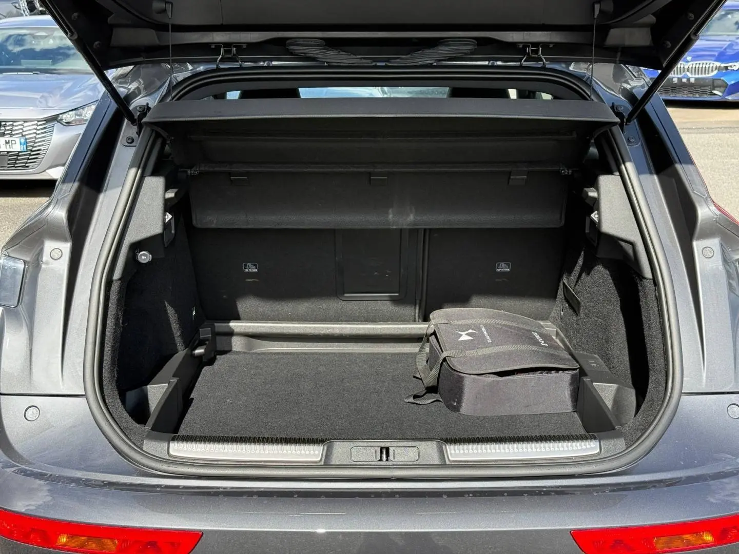 Coffre ouvert vu de l'arrière d'un DS7 E-TENSE gris titane avec sac de rangement noir à l'intérieur.