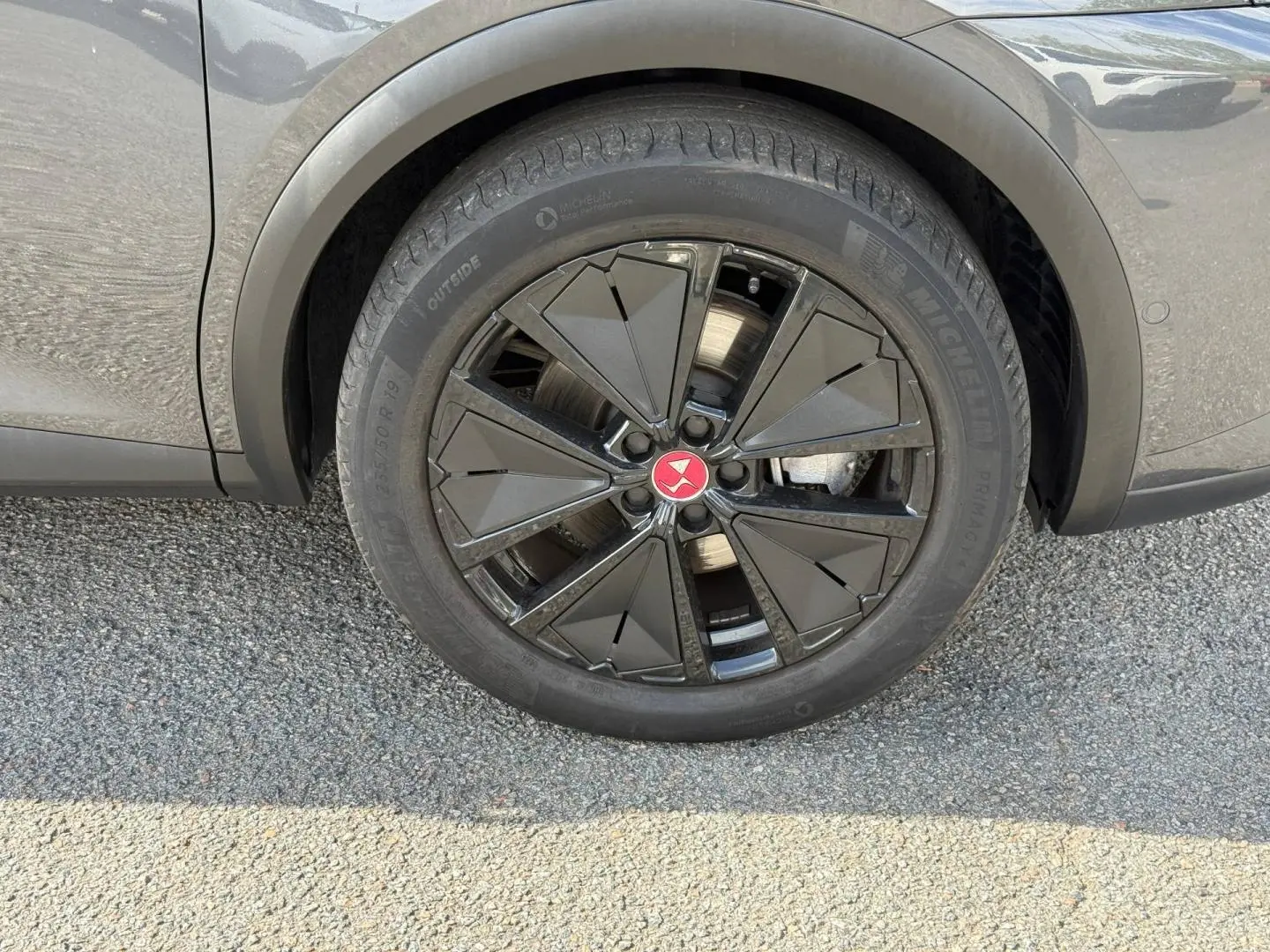 Gros plan sur la roue avant droite du DS7 E-TENSE 2024 en Gris Titane avec jante noire au design géométrique.