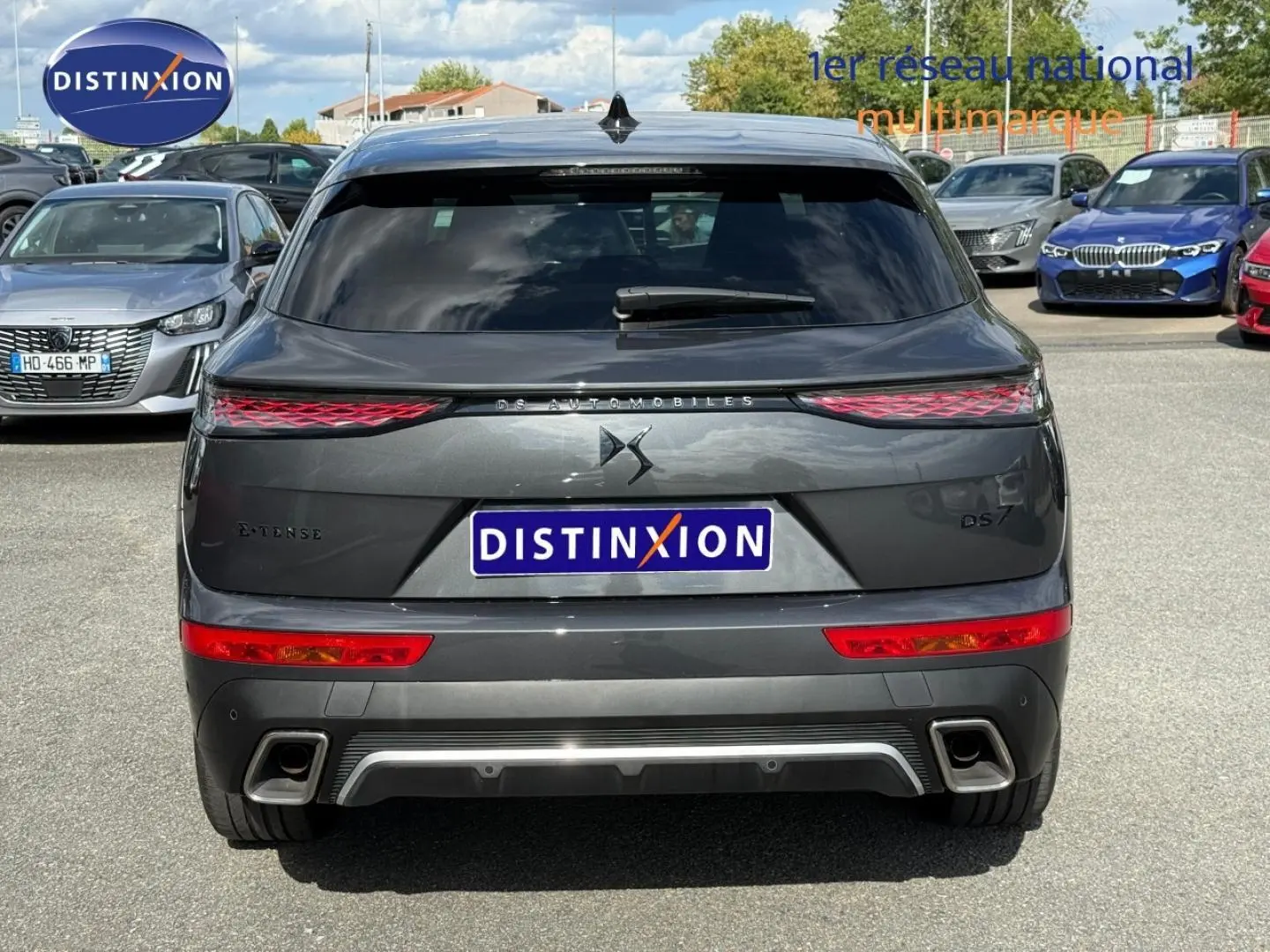 Vue arrière d’un DS7 E-TENSE gris titane 2024 avec feux LED et double sortie d’échappement visible en extérieur.