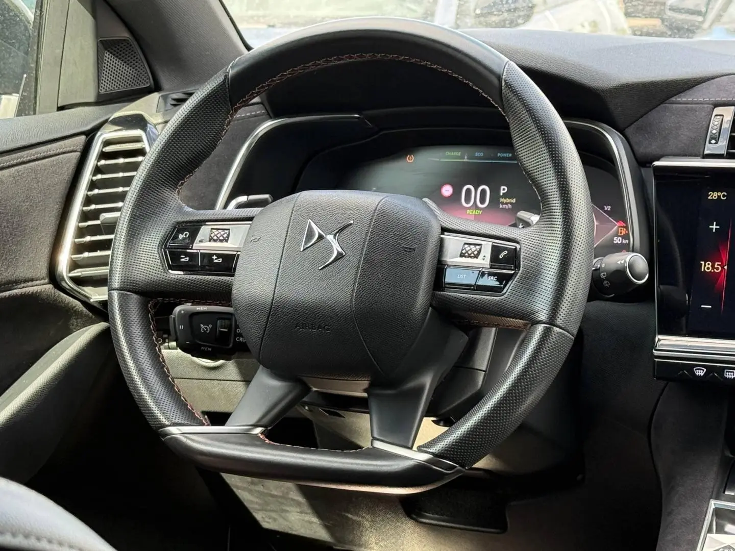 Vue rapprochée du volant cuir noir du DS7 E-TENSE 2024 avec tableau de bord numérique et commandes intégrées.