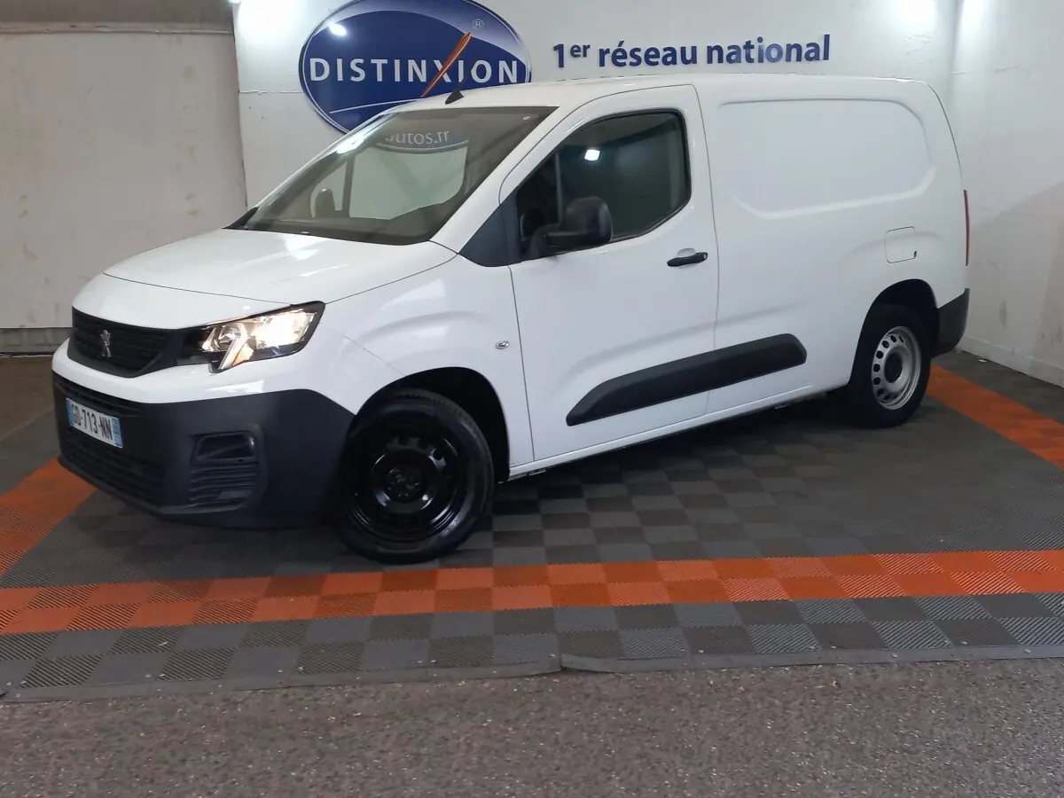 Vue 3/4 avant droit d’un utilitaire Peugeot Partner blanc avec pare-chocs noirs et jantes acier noires.