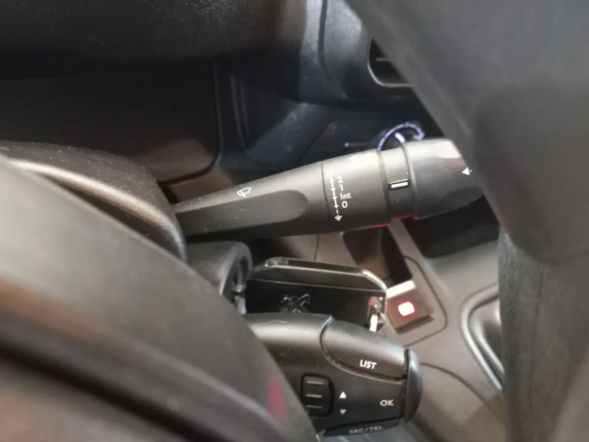 Gros plan sur la commande des essuie-glaces et du régulateur de vitesse dans l'habitacle du Peugeot Partner blanc.