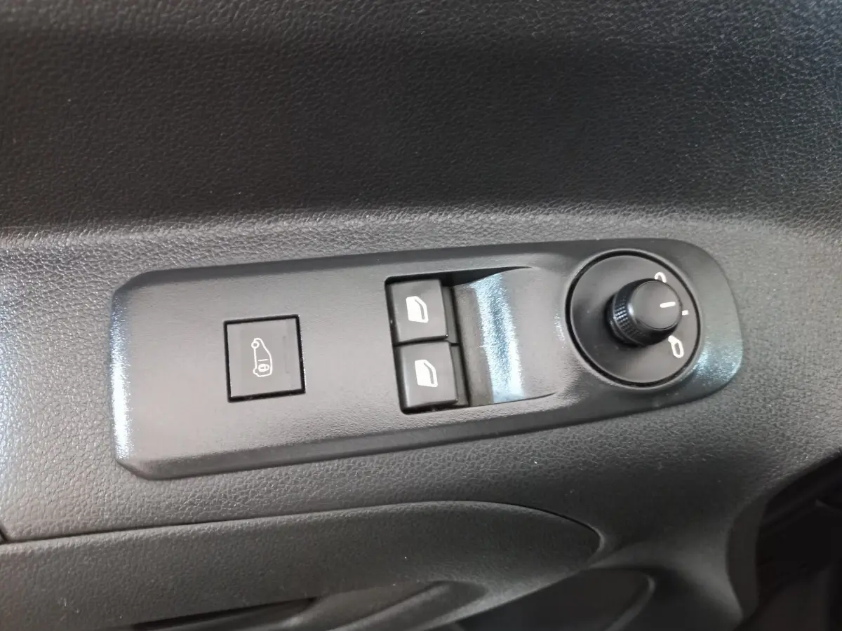 Gros plan sur les commandes de réglage des rétroviseurs et des vitres électriques sur la porte intérieure d'un Peugeot Partner blanc.