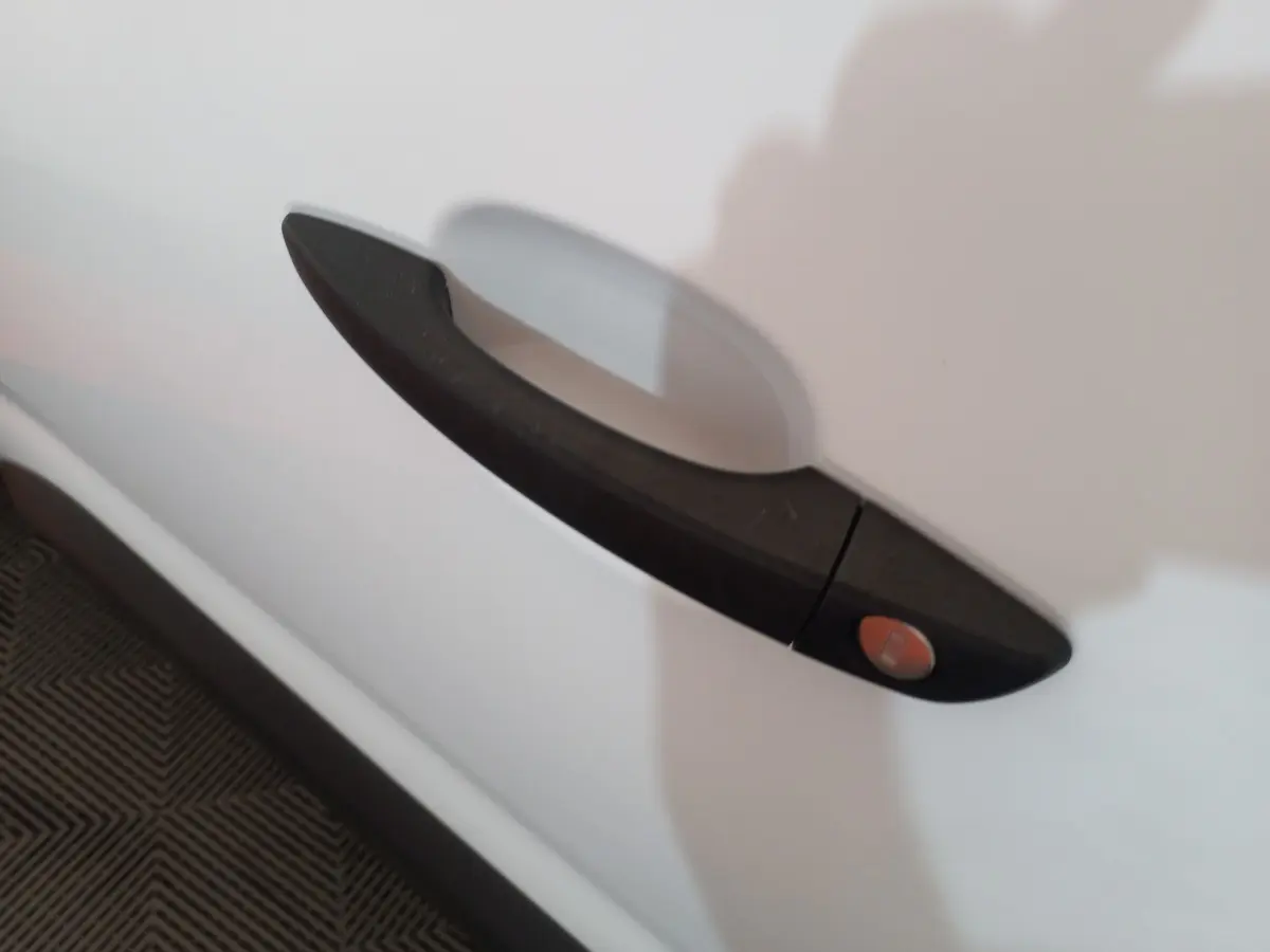 Poignée de porte noire en gros plan sur la porte blanche côté droit du Peugeot Partner BlueHDi 100 Long 2021.