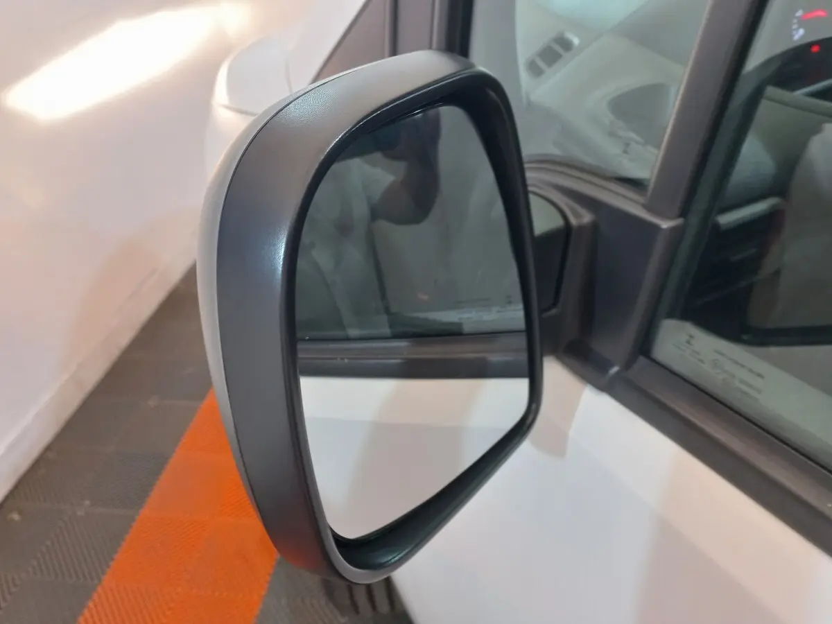 Gros plan sur le rétroviseur côté gauche du Peugeot Partner blanc, avec reflet partiel de l'intérieur du véhicule.