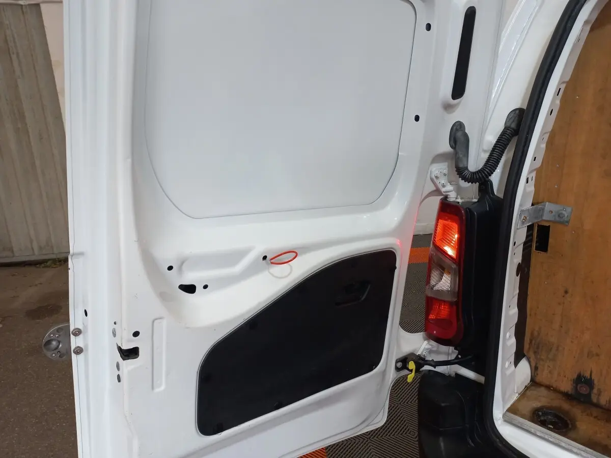 Vue rapprochée de la porte arrière droite blanche du Peugeot Partner 2021, avec feu arrière et intérieur bois visible.