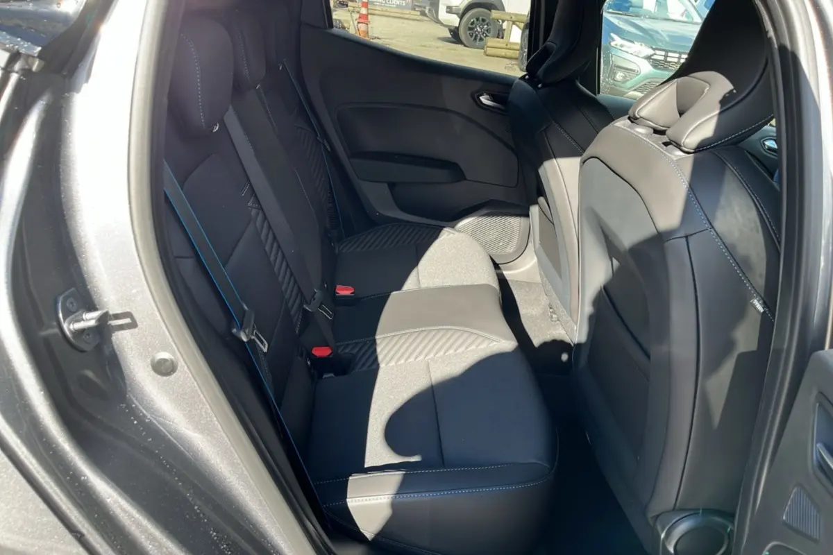 Vue intérieure arrière côté gauche de la Renault Clio V E-Tech 145 Esprit Alpine 2025 en gris schiste, sièges avec surpiqûres bleues.