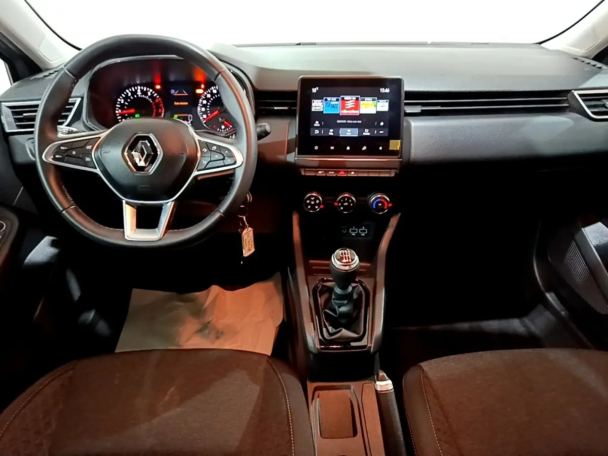 Vue intérieure centrée sur le tableau de bord et volant cuir de la Renault Clio 2023, avec écran tactile et boîte manuelle.