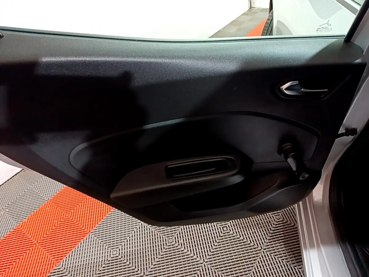 Vue intérieure sur la porte arrière droite noire de la Renault Clio gris clair avec poignée de fenêtre manuelle.