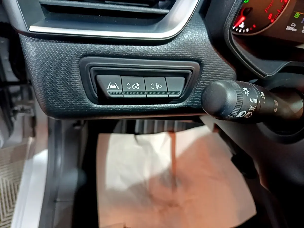 Vue intérieure côté gauche du tableau de bord gris clair de la Renault Clio 2023 avec commandes d'assistance et manette d'éclairage.