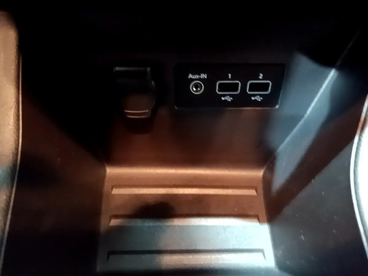 Gros plan sur la prise USB et port Aux-in dans le rangement central noir de la Renault Clio gris clair 2023.